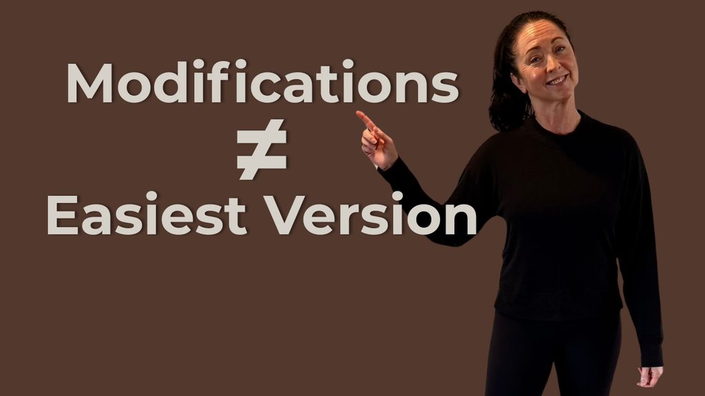 Yoga teacher Heather Otterbine pointing toward text that reads “Modifications ≠ Easiest Version.”